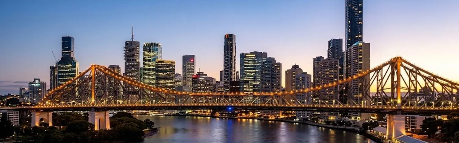 A city bridge lit at dusk, with the skyline behind it